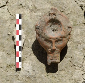 La lucerna, configurata con una testa virile, rinvenuta nella necropoli